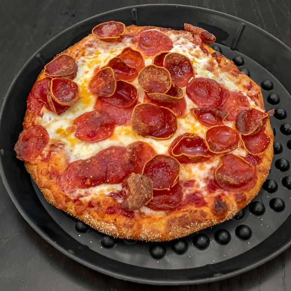 A freshly baked pepperoni pizza with melted cheese on a black, round pizza pan.